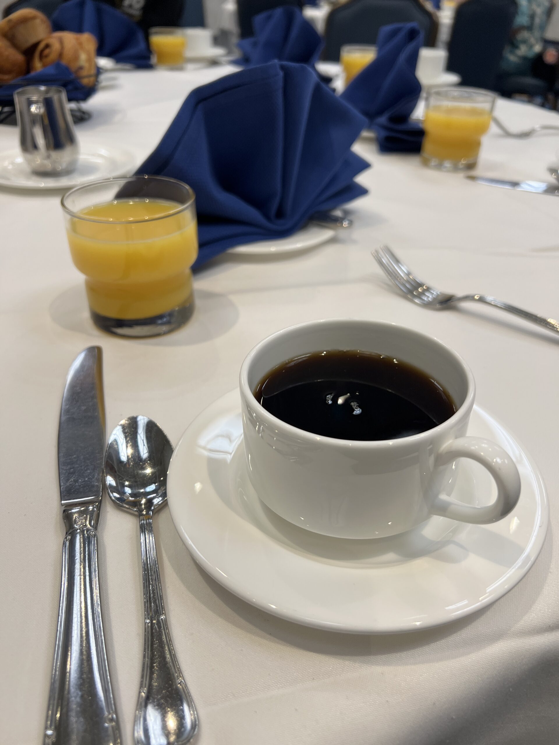 円卓の上のコーヒーとオレンジジュース、テーブルセットが並ぶ朝食会場