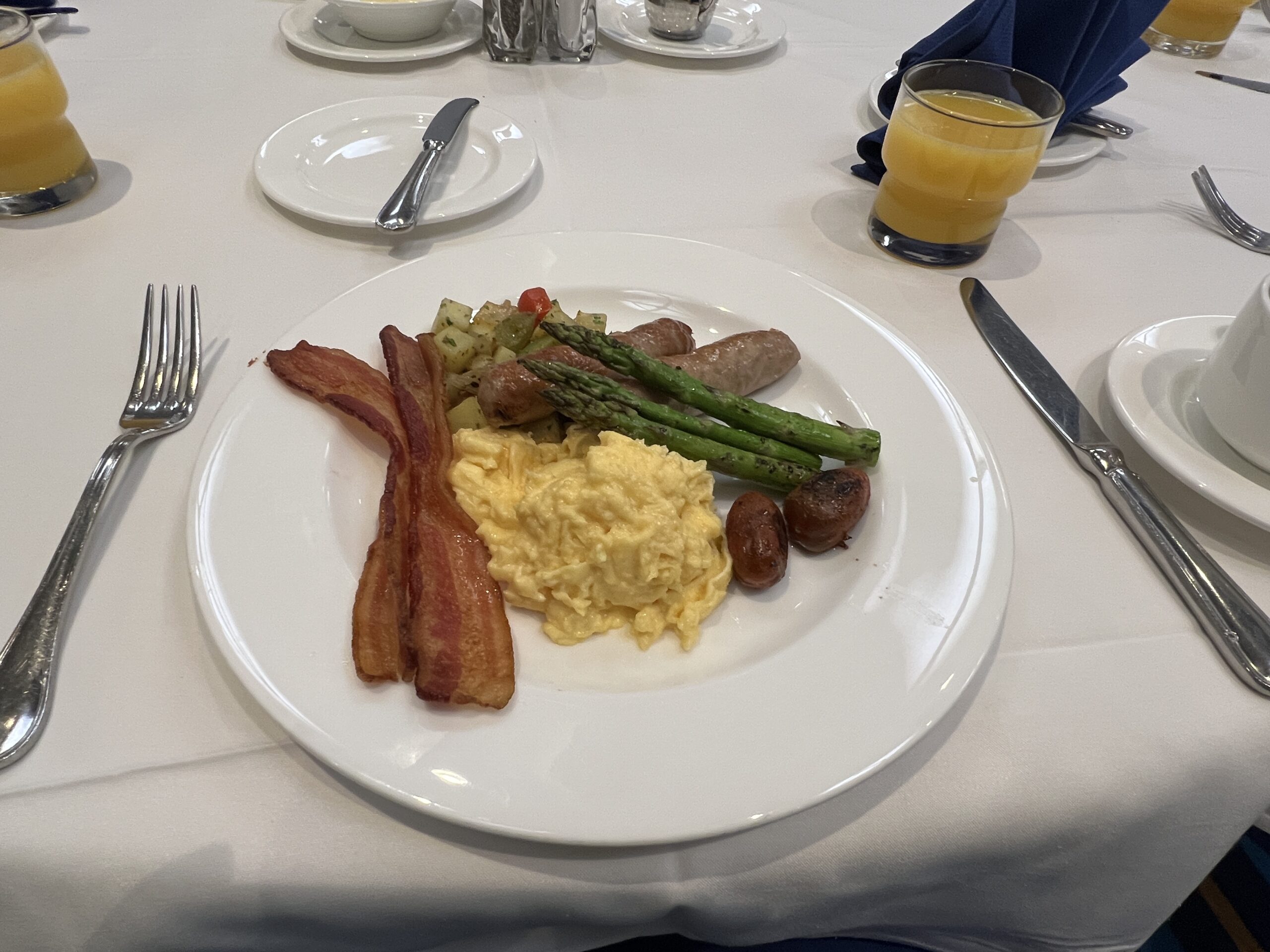 スクランブルエッグ、ベーコン、ソーセージ、アスパラソテーが盛られた朝食プレート